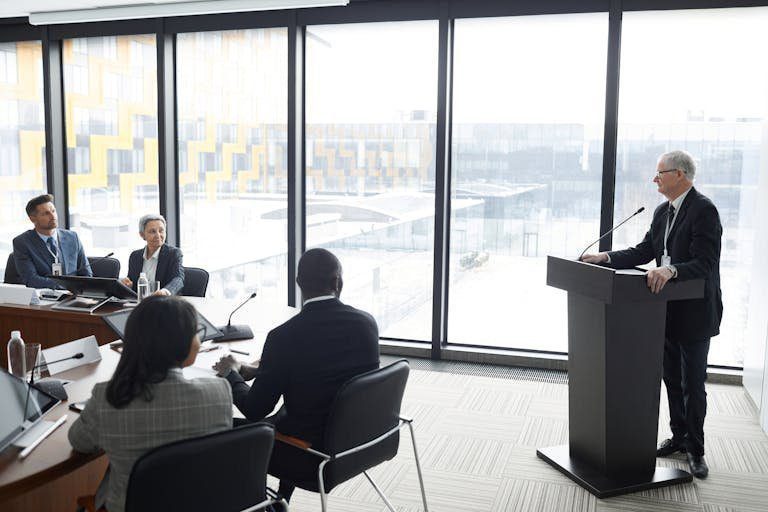 Corporate professionals engaged in a formal business meeting in a modern conference room setting.