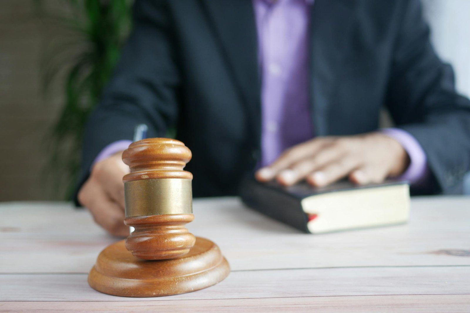 A wooden gavel and legal book represent justice in a court setting, emphasizing order and legal authority.